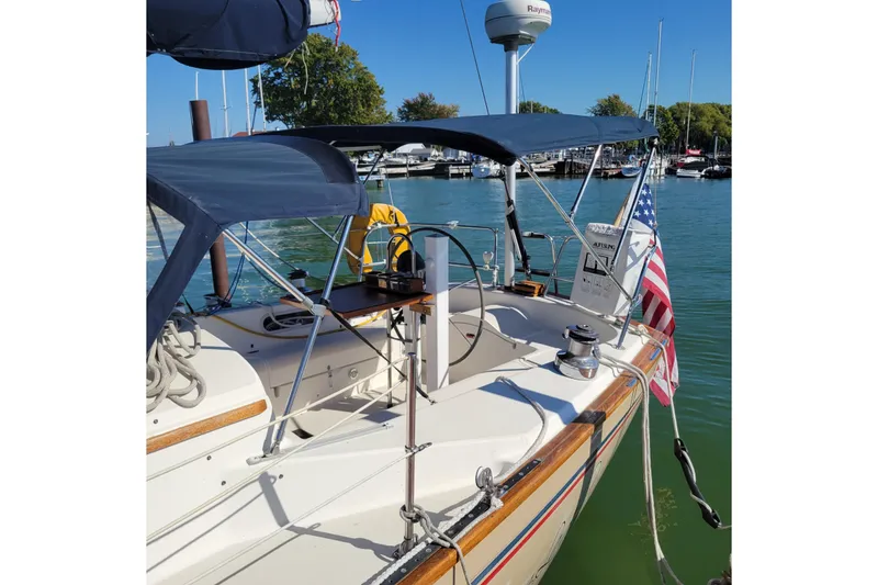 Slide: The Image of 1984 Pearson 386 sailboat docked, featuring blue canopy and American flag. - 16