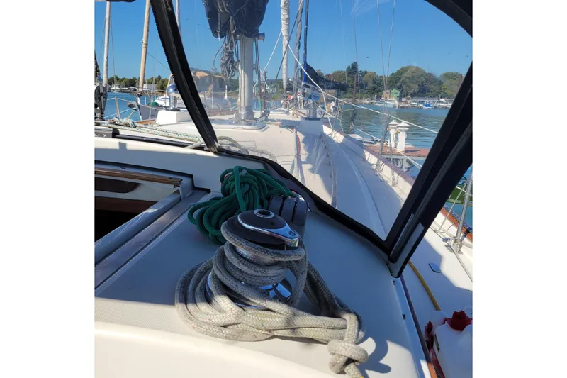 Slide: The Image of 1984 Pearson 386 sailboat deck with ropes and winch, docked in a serene marina. - 22