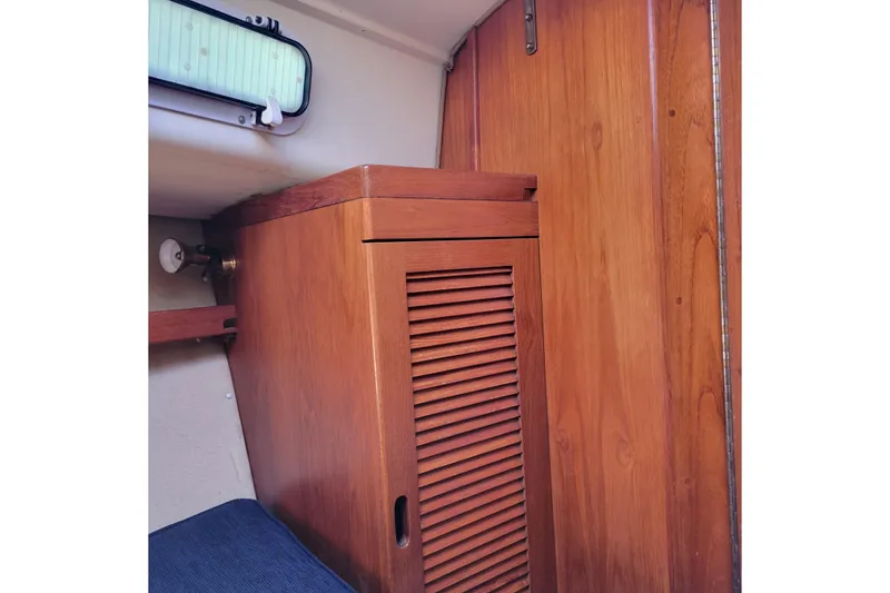 Slide: The Image of Wooden interior of 1984 Pearson 386 sailboat, featuring a louvered cabinet and porthole. - 36