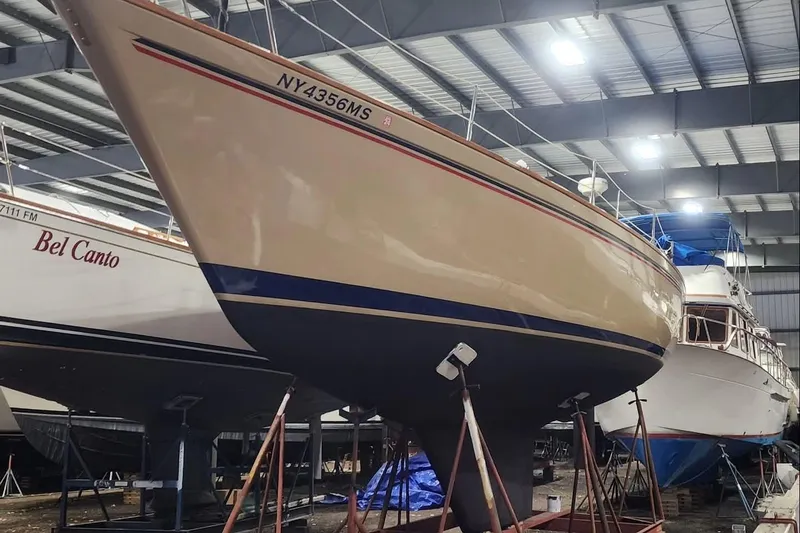 Slide: The Image of 1984 Pearson 386 sailboat in storage, supported by stands, with other boats nearby. - 45