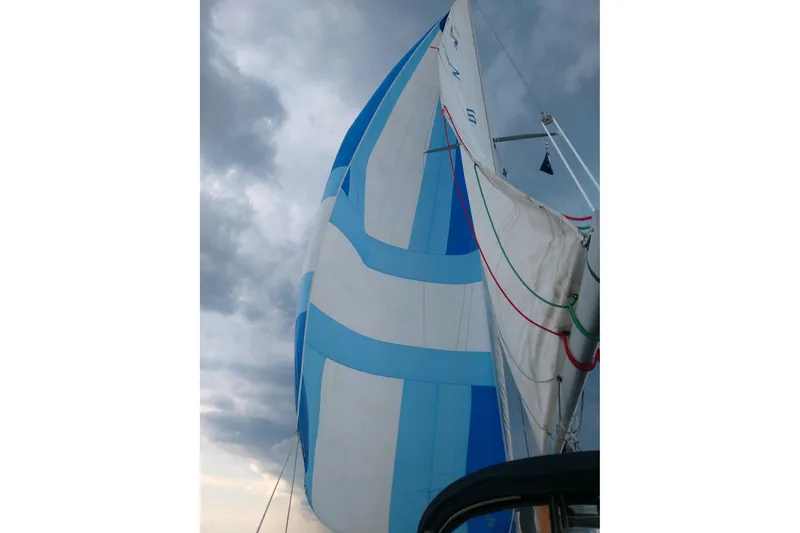 Slide: The Image of Sailing yacht Pearson 386 (1984) with blue and white sails against a cloudy sky. - 41