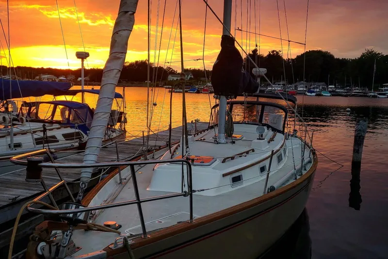 Slide: The Image of 1984 Pearson 386 sailboat docked at sunset, reflecting on calm water. - 48