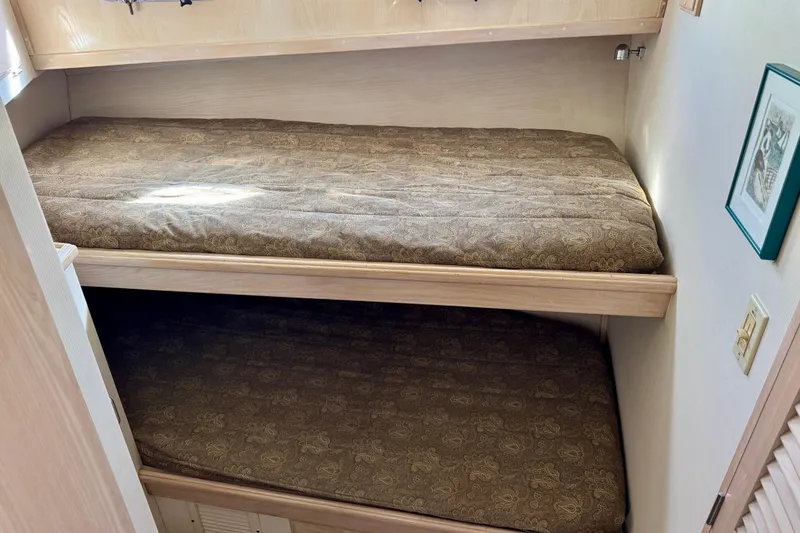 Slide: The Image of 1993 Tollycraft 57 Pilothouse Motor Yacht cabin with bunk beds and storage cabinets. - 19