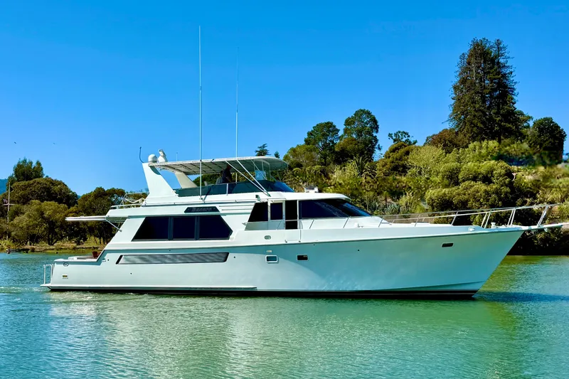 Slide: The Image of 1993 Tollycraft 57 Pilothouse Motor Yacht on serene water, surrounded by lush greenery. - 2