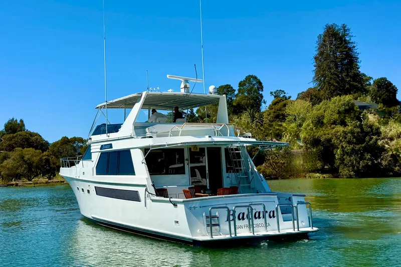 Slide: The Image of 1993 Tollycraft 57 Pilothouse Motor Yacht on serene water, surrounded by lush greenery. - 3
