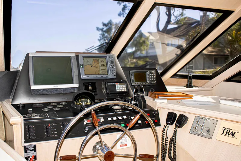 Slide: The Image of 1993 Tollycraft 57 Pilothouse Motor Yacht helm with steering wheel and navigation controls. - 38