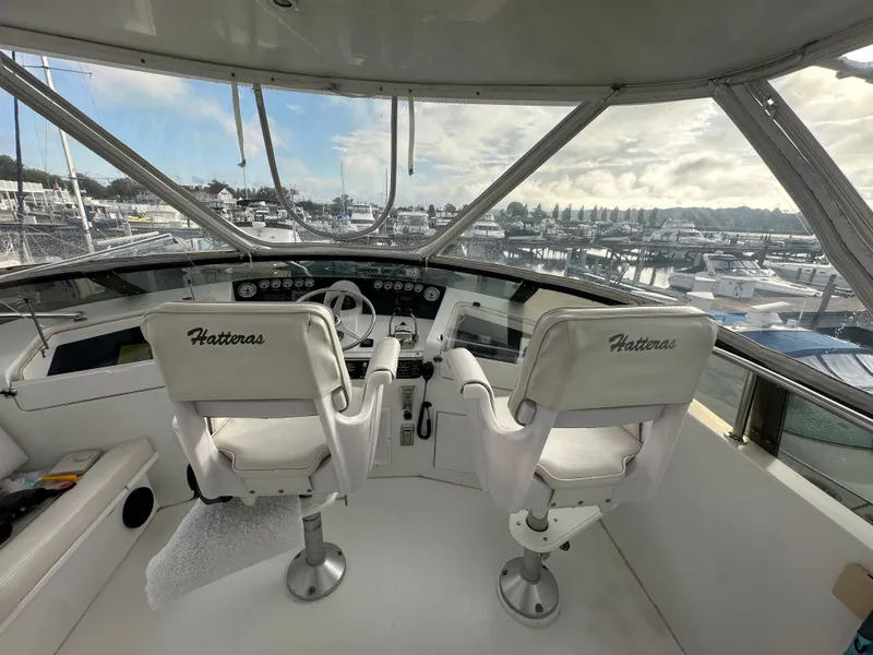 Slide: The Image of 1994 Hatteras 48 Cockpit MY helm with white seats overlooking marina. - 4