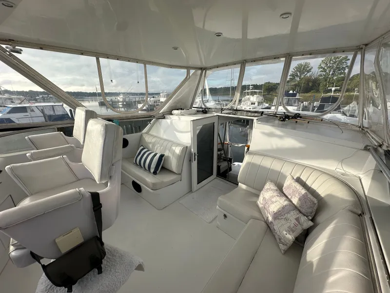 Slide: The Image of 1994 Hatteras 48 Cockpit MY interior with white seating and marina view. - 6