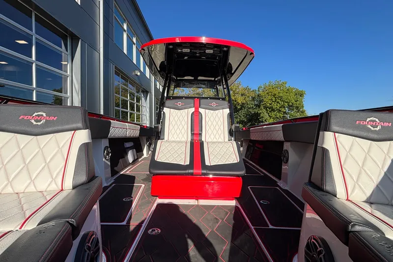Slide: The Image of 2021 Fountain 38 SC boat interior with red and white seating, docked near a building. - 36