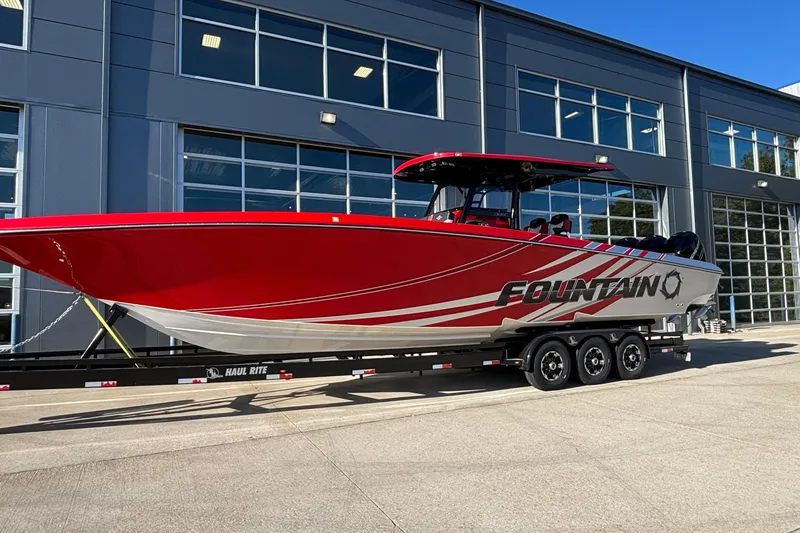 Slide: The Image of 2021 Fountain 38 SC boat in vibrant red on a trailer outside a modern building. - 37