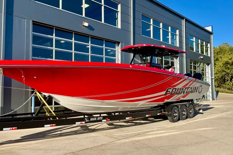 Slide: The Image of 2021 Fountain 38 SC boat in vibrant red, parked on a trailer outside a modern building. - 6