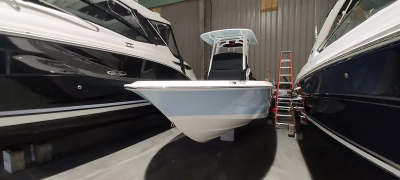 Slide: The Image of 2023 Boston Whaler 220 Dauntless boat in storage, flanked by two larger boats. - 14