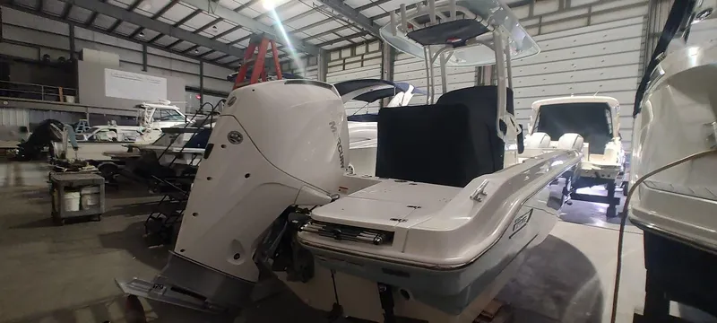 Slide: The Image of 2023 Boston Whaler 220 Dauntless boat in a warehouse, showcasing its sleek design and powerful engine. - 8