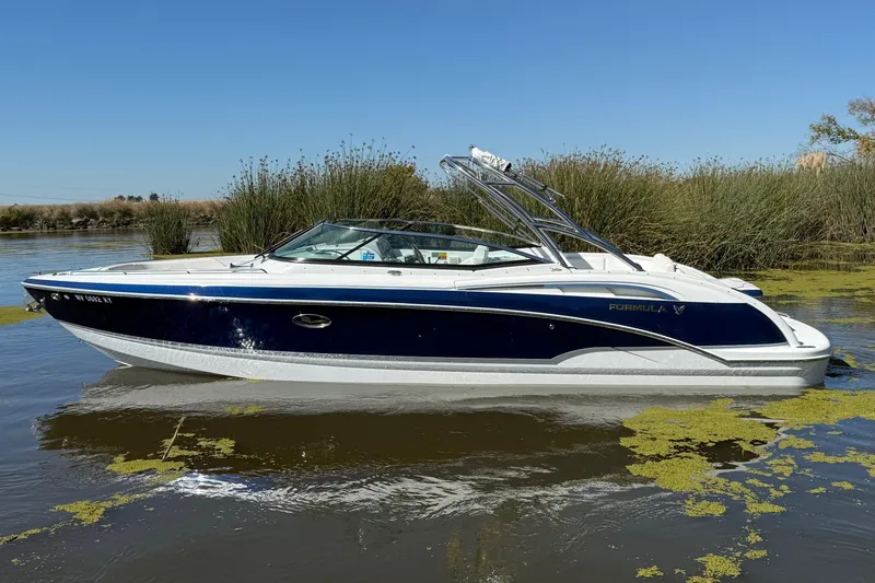 Slide: The Image of 2008 Formula 310 Bowrider boat on calm water with reeds in the background. - 2