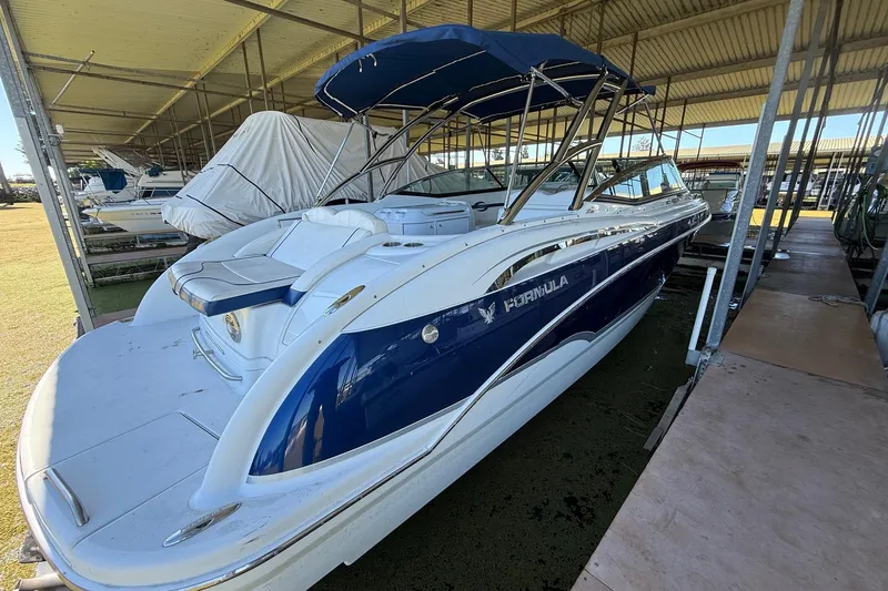 Slide: The Image of 2008 Formula 310 Bowrider boat with blue and white design, docked under a covered area. - 31