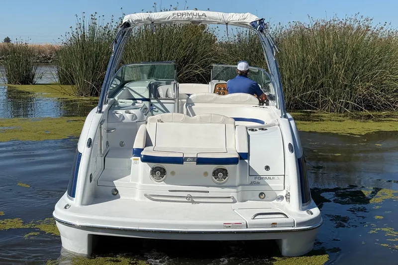 Slide: The Image of 2008 Formula 310 Bowrider boat navigating through a lush, green waterway. - 4