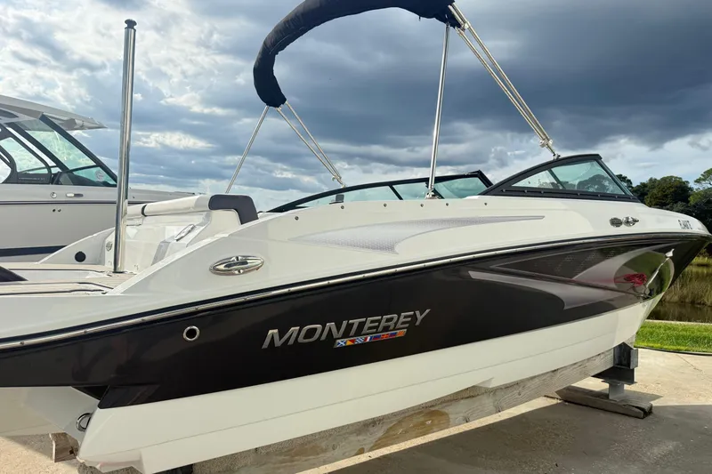 Slide: The Image of 2022 Monterey M-225 boat with sleek design, docked under cloudy sky. - 4