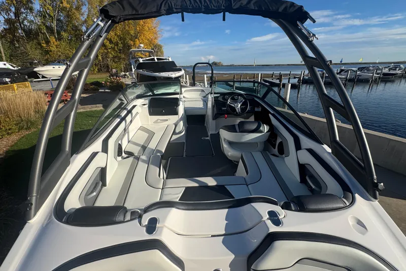 Slide: The Image of 2018 Yamaha Boats AR195 interior with sleek seating and modern design at a marina. - 19