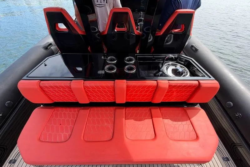 Slide: The Image of Red seating and console on 2023 Skipper-BSK 42NC boat, featuring sleek design and water backdrop. - 17