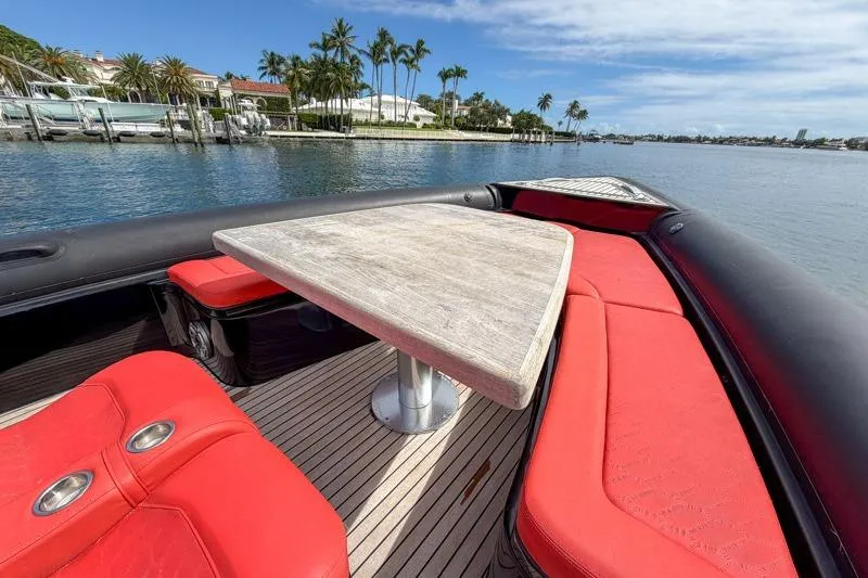 Slide: The Image of 2023 Skipper-BSK 42NC boat with red seating and wooden table on a sunny waterfront. - 21