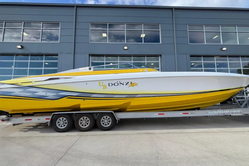 Slide: The Image of 2002 Donzi 45 ZX powerboat in vibrant yellow on a trailer, parked outside a modern building. - 47