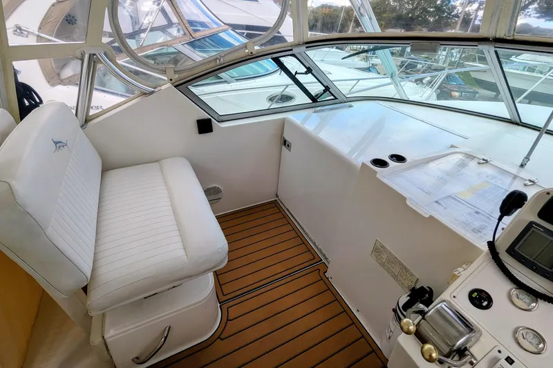 Slide: The Image of 2002 Stamas 340 Express boat cockpit with white seating and wooden flooring. - 19