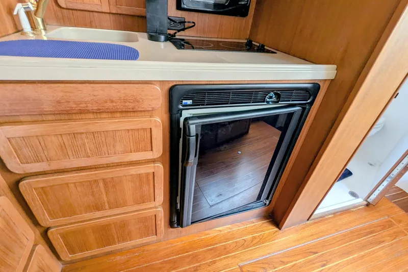 Slide: The Image of 2002 Stamas 340 Express boat kitchen with wooden cabinets and compact refrigerator. - 29