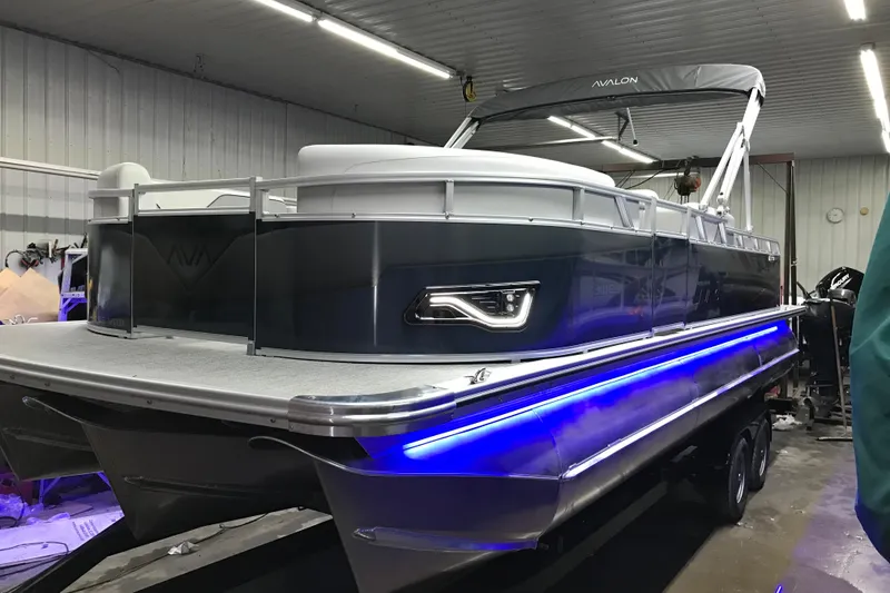Slide: The Image of 2026 Avalon Venture 85 Versatile rear Bench pontoon boat in a well-lit garage. - 23
