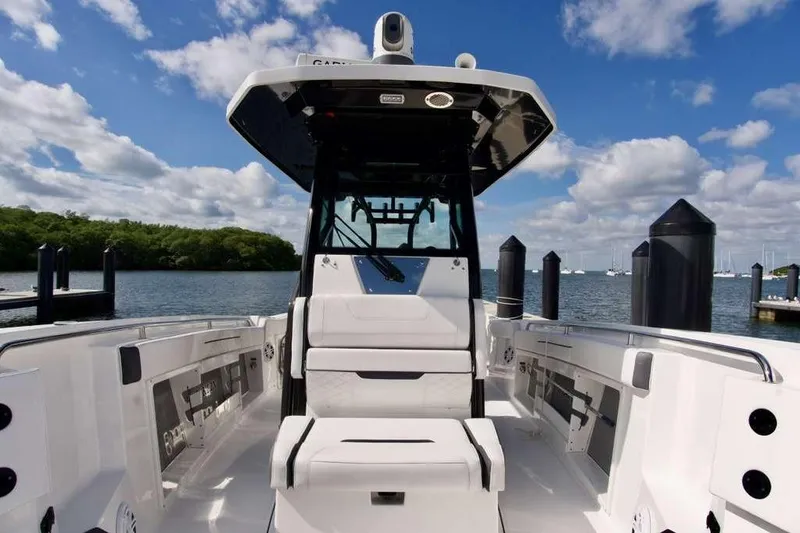 Slide: The Image of 2023 Blackfin 302 CC boat interior with seating, docked by a scenic waterfront. - 36