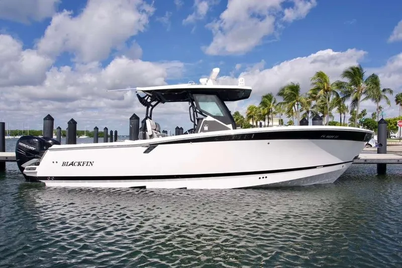 Slide: The Image of 2023 Blackfin 302 CC boat docked by palm trees under a blue sky. - 6