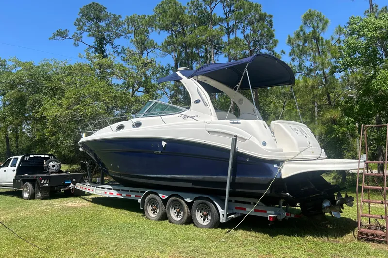Slide: The Image of 2006 Sea Ray 300 Sundancer boat on trailer, surrounded by trees and grass. - 15