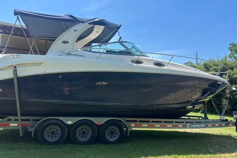 Slide: The Image of 2006 Sea Ray 300 Sundancer boat on trailer, parked outdoors under clear blue sky. - 17