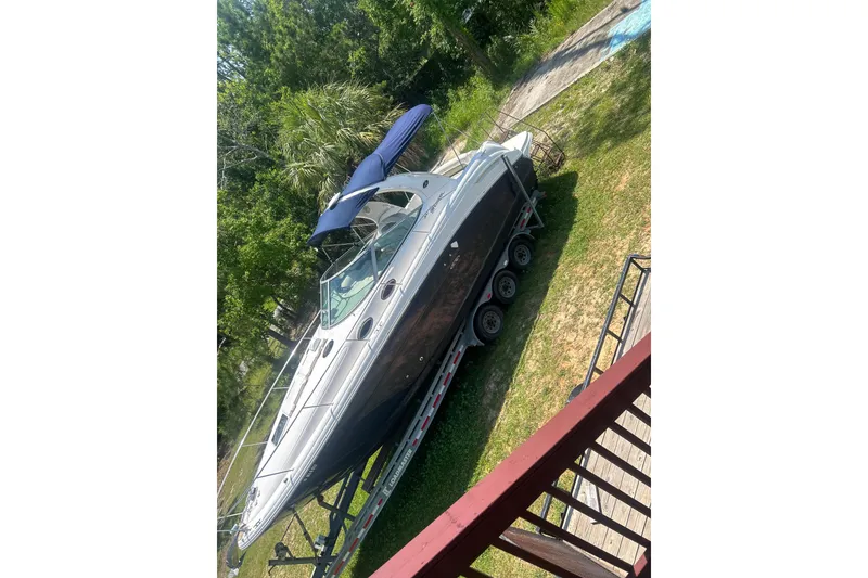 Slide: The Image of 2006 Sea Ray 300 Sundancer boat on trailer, surrounded by greenery. - 23