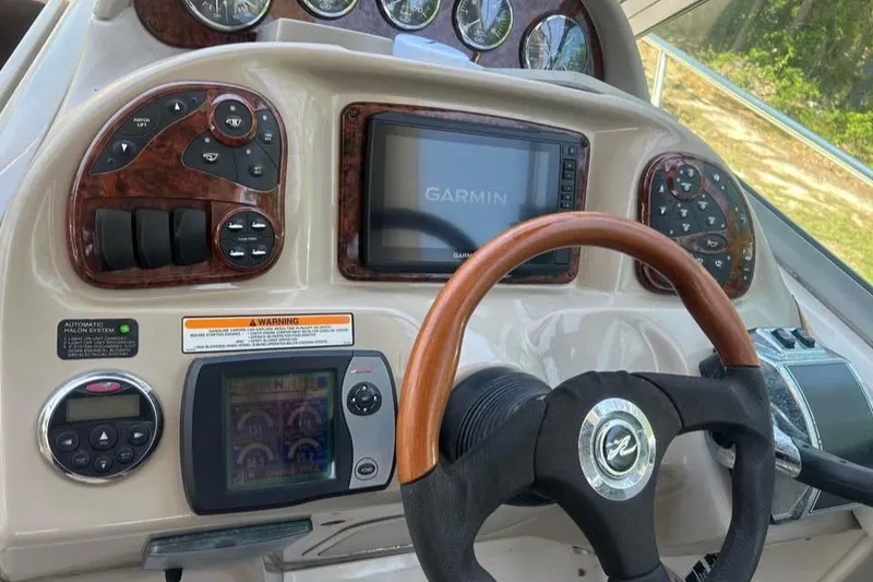 Slide: The Image of 2006 Sea Ray 300 Sundancer dashboard with Garmin navigation and wood-trimmed steering wheel. - 31
