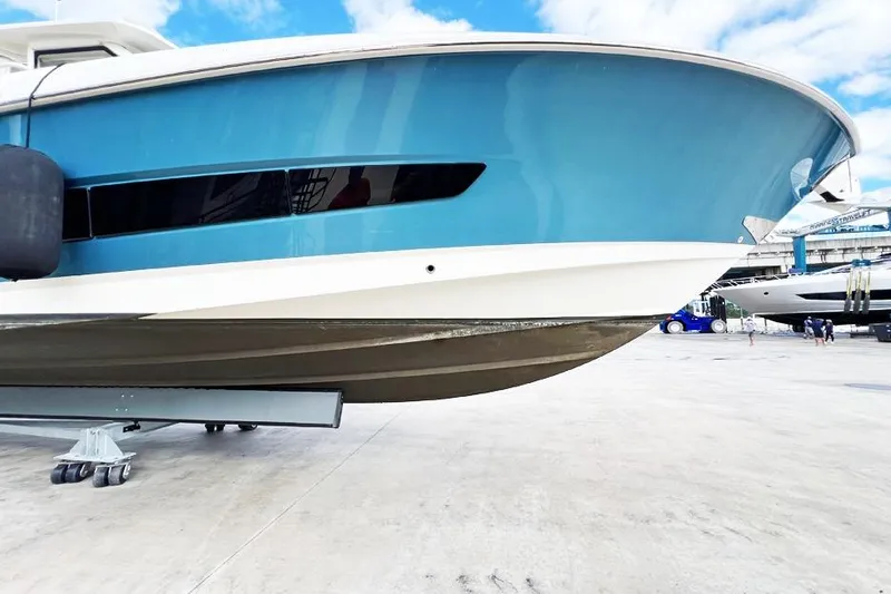 Slide: The Image of 2018 Boston Whaler 420 Outrage boat on dry dock, blue hull, clear sky background. - 25