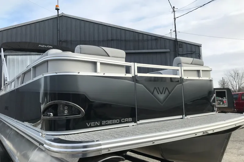 Slide: The Image of 2026 Avalon Venture Cruise Rear Bench pontoon boat, sleek design, parked outdoors. - 3