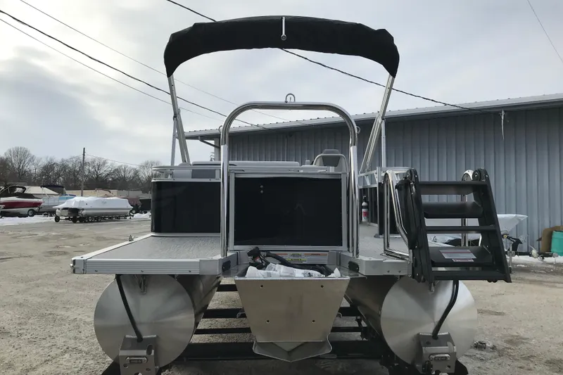 Slide: The Image of 2026 Avalon Venture Cruise Rear Bench pontoon boat with canopy in a storage yard. - 6