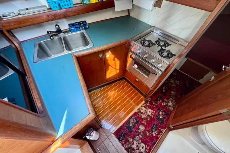 Slide: The Image of 1989 Bayliner 3288 Motoryacht kitchen with stove, sink, and wooden cabinetry. - 10