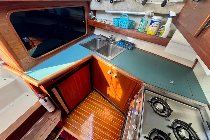 Slide: The Image of 1989 Bayliner 3288 Motoryacht kitchen with stove, sink, and cleaning supplies. - 13