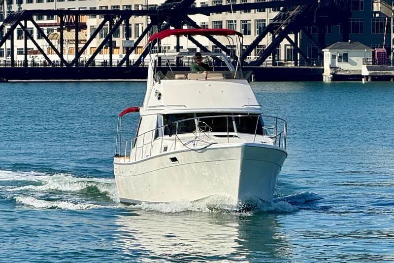 Slide: The Image of 1989 Bayliner 3288 Motoryacht cruising on water near industrial backdrop. - 4