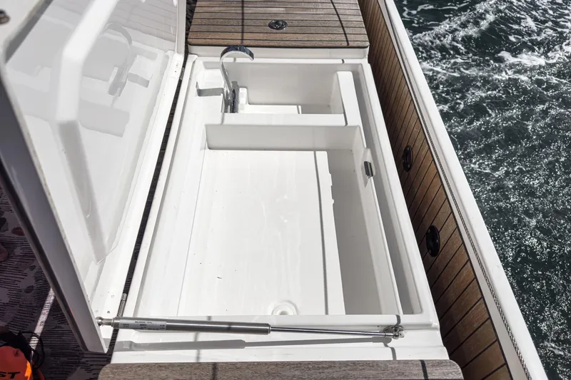 Slide: The Image of 2023 Bavaria C50 yacht deck with open storage compartment and ocean view. - 27