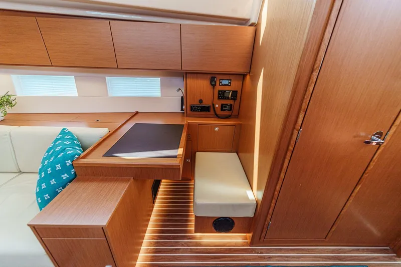 Slide: The Image of 2023 Bavaria C50 yacht interior with wooden cabinetry, navigation station, and cushioned seating. - 45