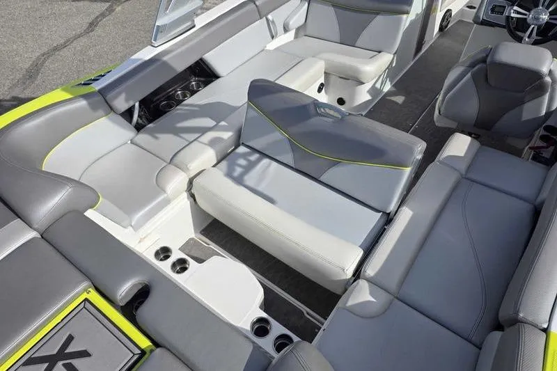 The Image of 2017 MasterCraft XT23 boat in vibrant lime green on a trailer, parked outdoors. - 2