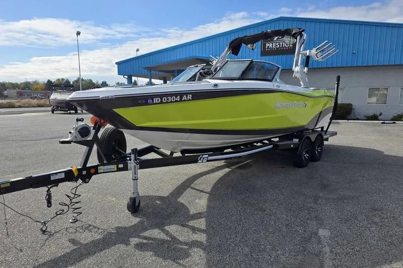 Slide: The Image of 2017 MasterCraft XT23 boat in vibrant lime green on a trailer in a parking lot. - 5