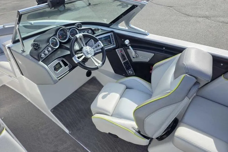 Slide: The Image of 2017 MasterCraft XT23 boat on trailer, lime green and black, parked outside a blue building. - 6