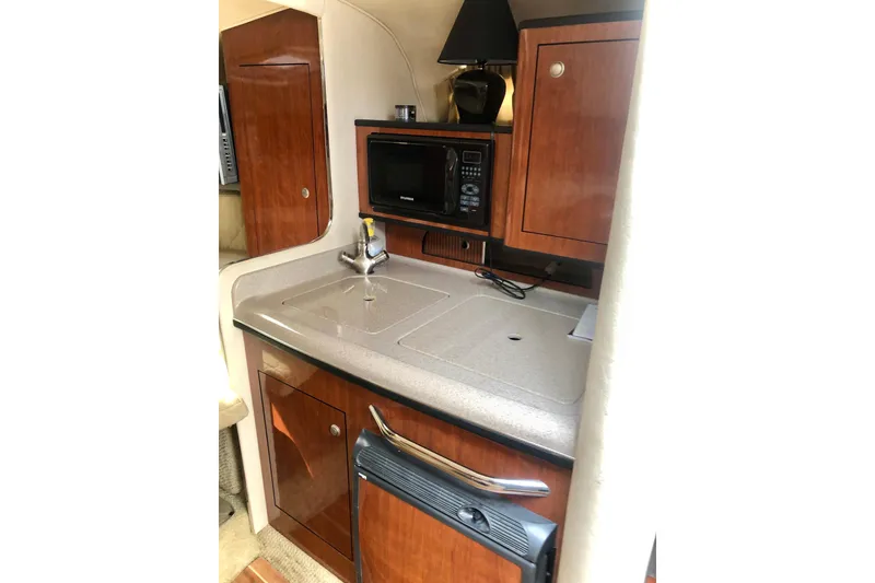 Slide: The Image of 2007 Sea Ray 280 Sundancer galley with sink, microwave, and wooden cabinetry. - 5