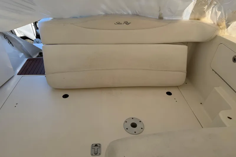 Slide: The Image of 2007 Sea Ray Sundancer 280 interior seating area with white upholstery and storage compartments. - 14