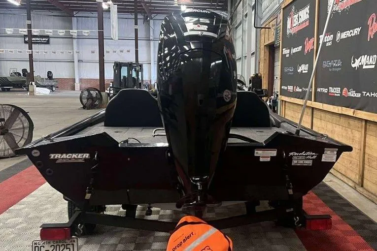Slide: The Image of 2024 Tracker Pro Team 175 TXW boat in a showroom, rear view with Mercury engine. - 5