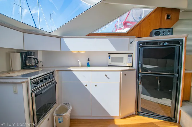 Slide: The Image of 1996 Silverton 372 Motor Yacht kitchen with stove, microwave, and fridge under skylight. - 13