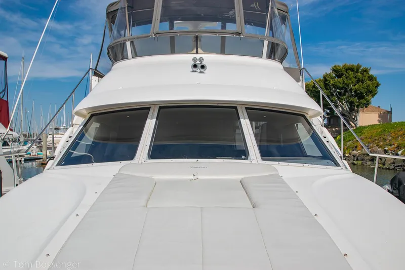 Slide: The Image of 1996 Silverton 372 Motor Yacht docked, showcasing sleek design and spacious deck under clear blue sky. - 49